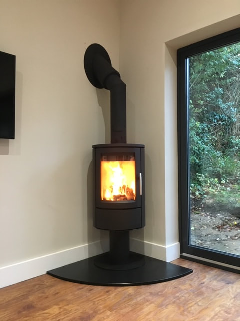 HWAM wood burning stove on a pedestal with twin wall flue