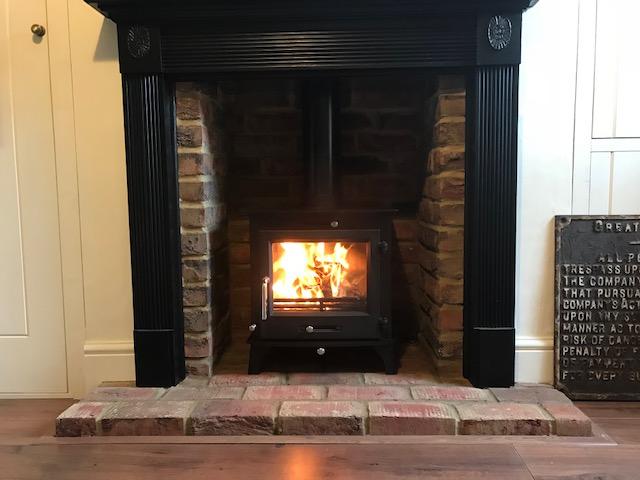 Clock wood stove with timber fire surround. Sevenoaks install